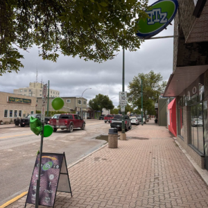 image of store front with Indigenous dancer performing outside on sidewalk