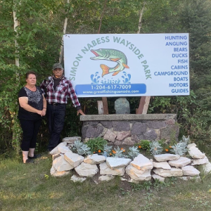 Owners standing in front of their new welcome sign