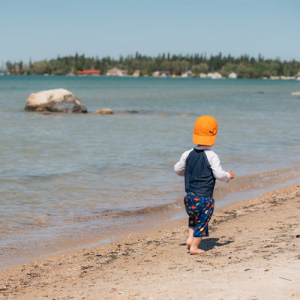 Toddler walking barefoot along the beach at Pioneer Bay