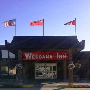Front entrance of the hotel that has three flags blowing in the wind