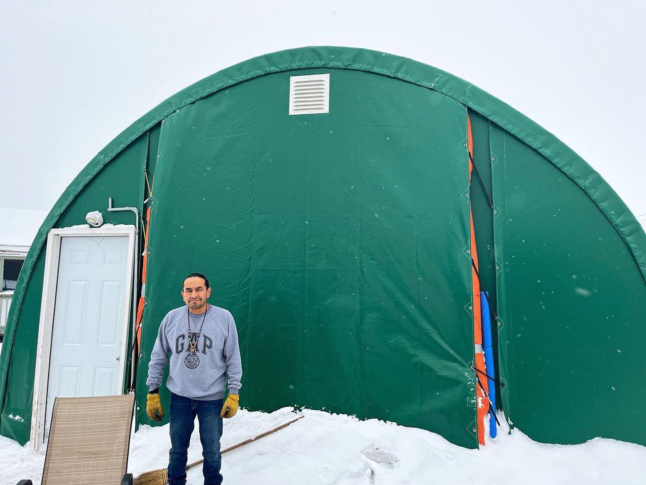 Sherwin is standing outside the quonset that houses the sweat lodge in the winter