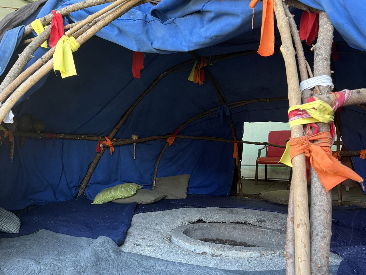 interior of the sweat lodge, Mother Earth pit in the centre with pillows and blankets covering the ground